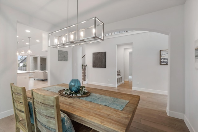 318 Mistletoe Ridge Ct, Montgomery, TX 77316 - dining area featuring an inviting chandelier, arched walkways, baseboards, and light wood-style floors