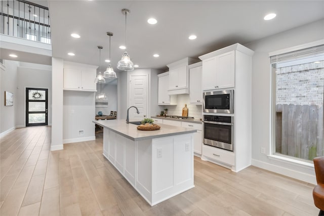 318 Mistletoe Ridge Ct, Montgomery, TX 77316 - kitchen featuring light wood finished floors, stainless steel appliances, and white cabinetry