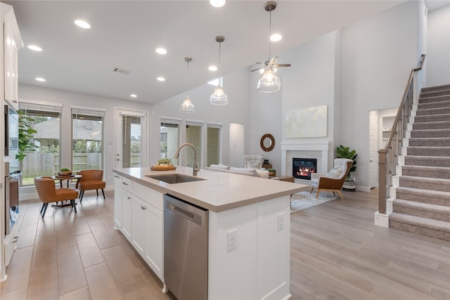 318 Mistletoe Ridge Ct, Montgomery, TX 77316 - kitchen featuring a glass covered fireplace, ceiling fan, a sink, stainless steel appliances, and light wood-type flooring