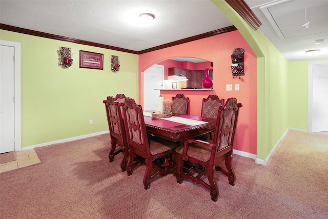 carpeted dining area with crown molding, attic access, arched walkways, and baseboards