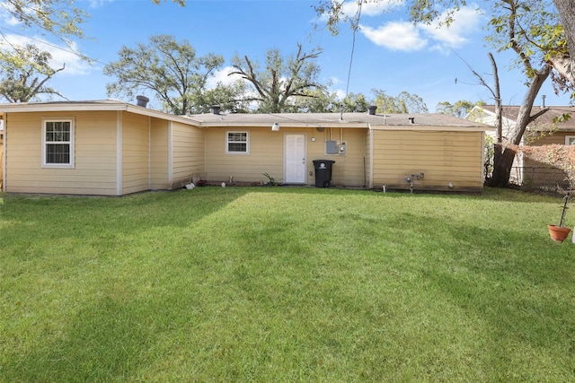rear view of house featuring a yard and fence