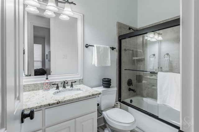 bathroom with vanity, combined bath / shower with glass door, ensuite bath, and toilet