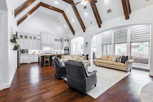 living area with arched walkways, high vaulted ceiling, dark wood-type flooring, a ceiling fan, and beamed ceiling