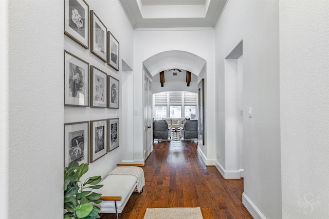 hall with arched walkways, wood finished floors, baseboards, and ornamental molding