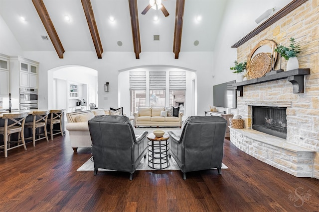 living room featuring ceiling fan, dark wood finished floors, arched walkways, a fireplace, and recessed lighting