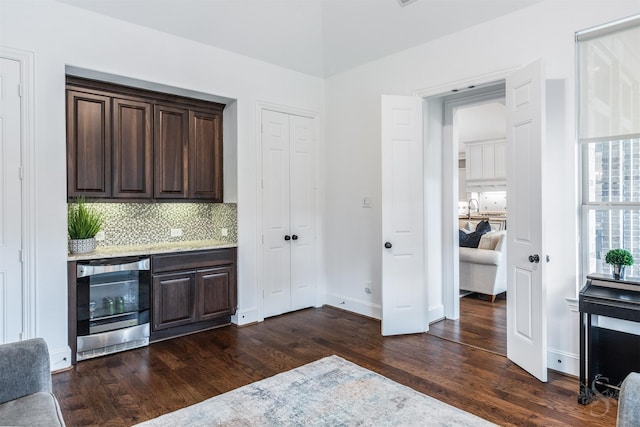 bar area featuring wine cooler, dark wood-type flooring, tasteful backsplash, baseboards, and a sink