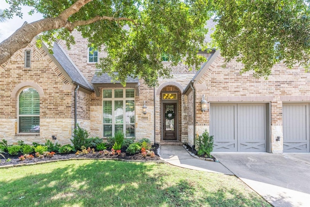 tudor house with driveway, a front lawn, a shingled roof, brick siding, and an attached garage
