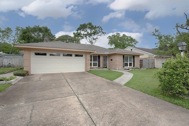 ranch-style home featuring a garage, fence, concrete driveway, a front lawn, and brick siding