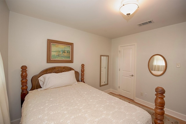 bedroom with wood finished floors, visible vents, and baseboards