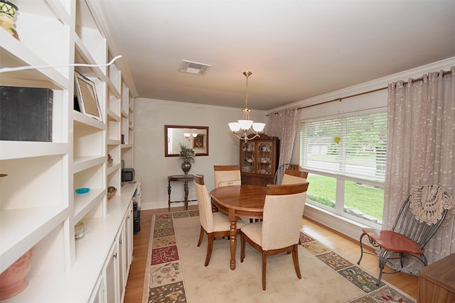dining area with light wood-type flooring, visible vents, an inviting chandelier, crown molding, and baseboards
