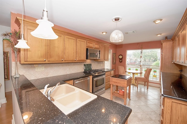 kitchen featuring backsplash, stainless steel appliances, visible vents, and a sink