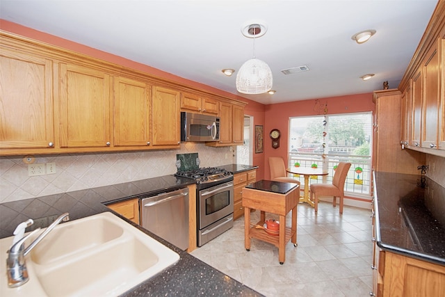 kitchen featuring a sink, stainless steel appliances, pendant lighting, visible vents, and decorative backsplash