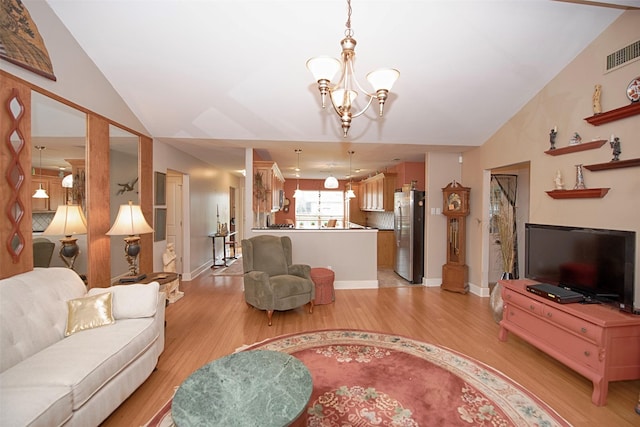 living room featuring visible vents, vaulted ceiling, a chandelier, light wood-style flooring, and baseboards