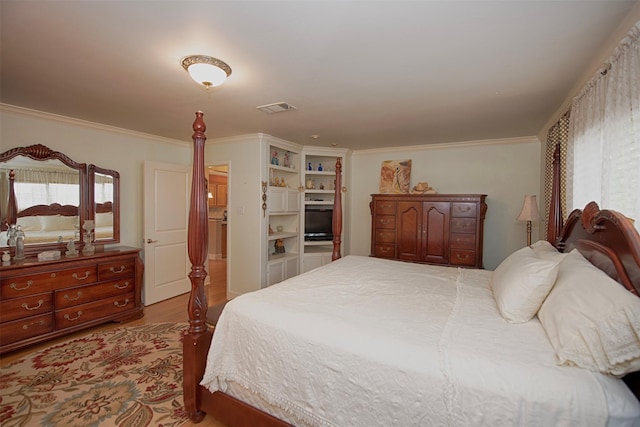 bedroom featuring ornamental molding, visible vents, and wood finished floors