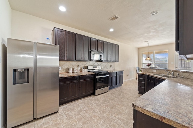 1902 Red Cedar Trl, Rosenberg, TX 77471 - kitchen featuring a sink, stainless steel appliances, dark brown cabinetry, visible vents, and decorative backsplash
