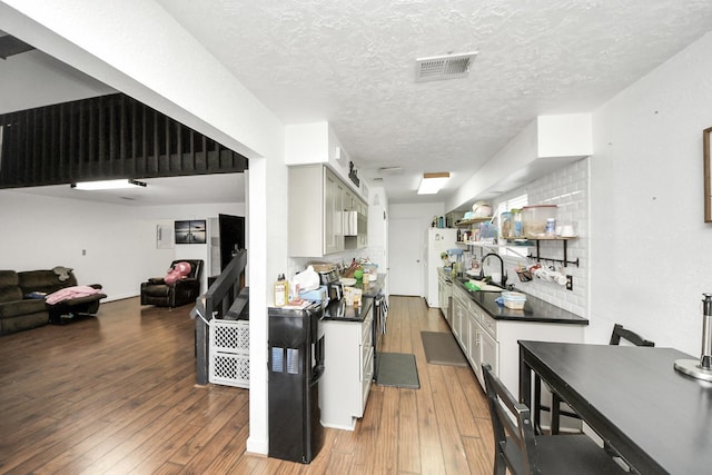 6230 Grandvale Dr, Houston, TX 77072 - kitchen with a textured ceiling, visible vents, light wood-style flooring, open floor plan, and dark countertops