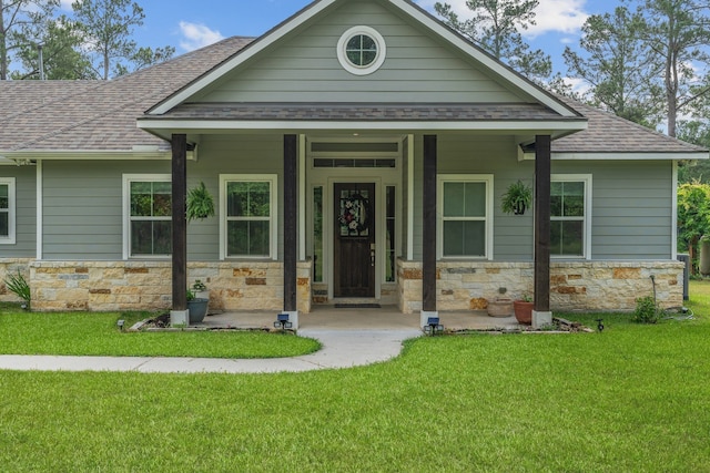 view of front of house with stone siding, roof with shingles, and a front lawn