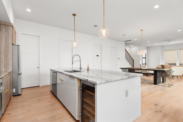 5203 Texas St, Houston, TX 77011 - kitchen featuring a sink, stainless steel appliances, a center island with sink, light wood-type flooring, and wine cooler