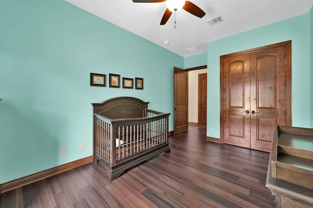 bedroom with a closet, visible vents, dark wood finished floors, a ceiling fan, and baseboards