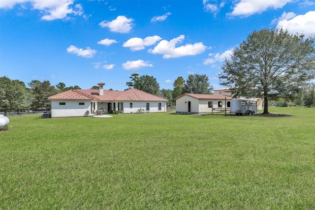back of property with stucco siding, fence, and a lawn
