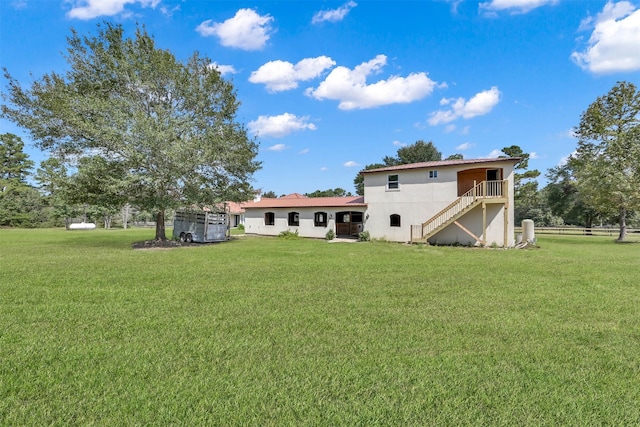 back of property with stairway and a yard