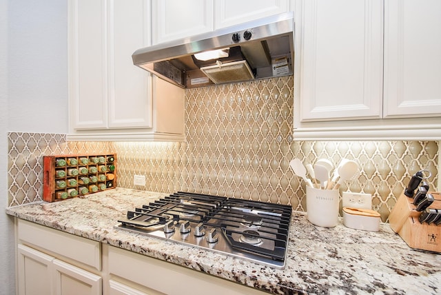 18273 Evanhale Bend Dr, Cypress, TX 77429 - kitchen featuring under cabinet range hood, stainless steel gas stovetop, decorative backsplash, white cabinetry, and light stone countertops
