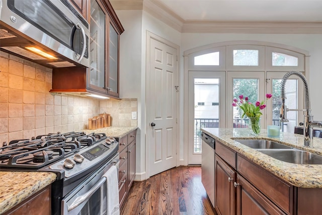 kitchen featuring crown molding, appliances with stainless steel finishes, a wealth of natural light, and a sink