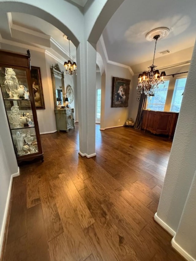 unfurnished dining area featuring crown molding, a notable chandelier, arched walkways, and a healthy amount of sunlight