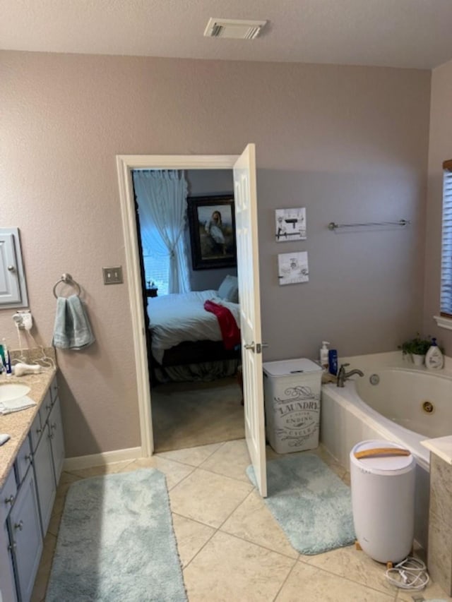 ensuite bathroom with tile patterned floors, visible vents, a jetted tub, and vanity