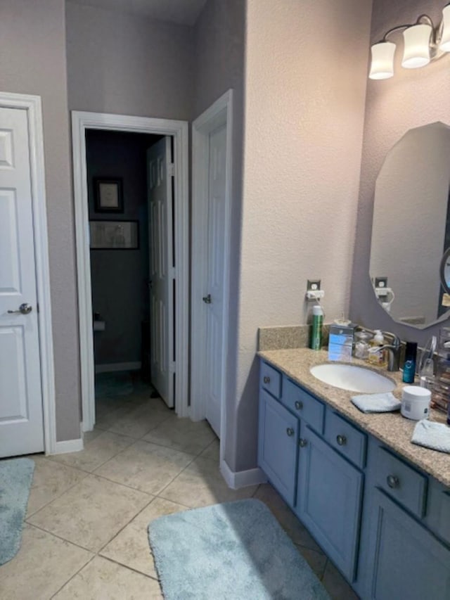bathroom with baseboards, tile patterned flooring, and vanity