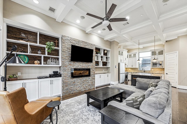 living area with light wood finished floors, ornamental molding, a ceiling fan, and visible vents