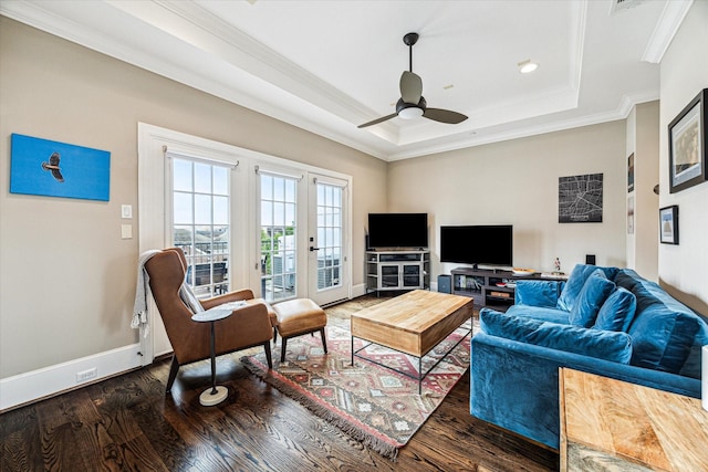 living area featuring a tray ceiling, crown molding, wood finished floors, and ceiling fan