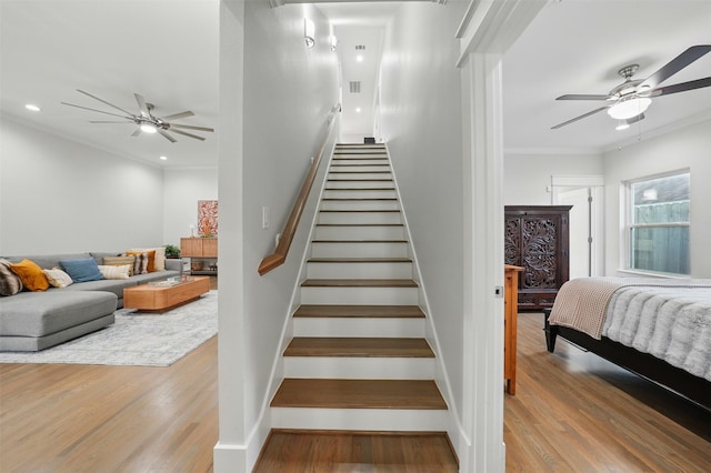 staircase with a ceiling fan, wood finished floors, crown molding, and recessed lighting