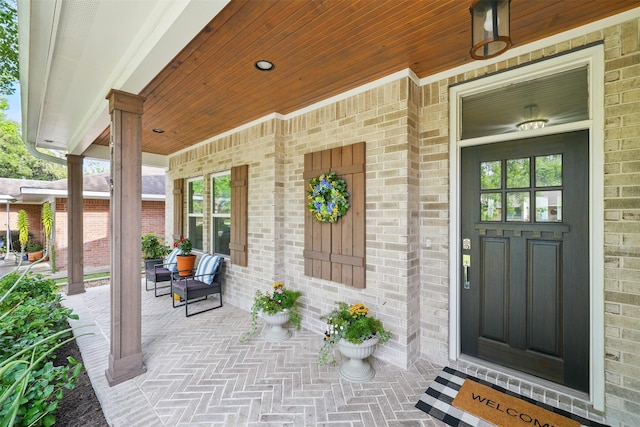 property entrance featuring covered porch and brick siding