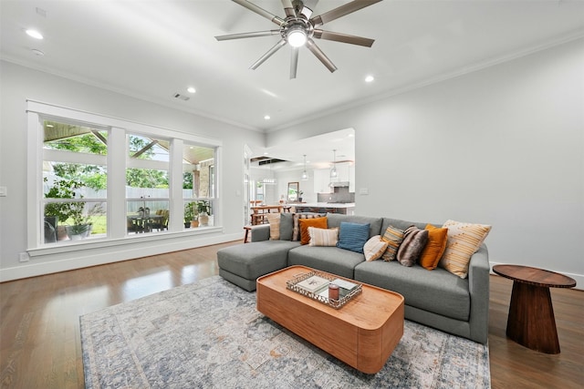 living room with crown molding, a ceiling fan, wood finished floors, recessed lighting, and baseboards