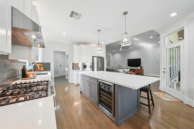 kitchen with wine cooler, appliances with stainless steel finishes, a sink, backsplash, and white cabinetry