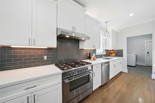 kitchen featuring appliances with stainless steel finishes, under cabinet range hood, a sink, washer / dryer, and tasteful backsplash