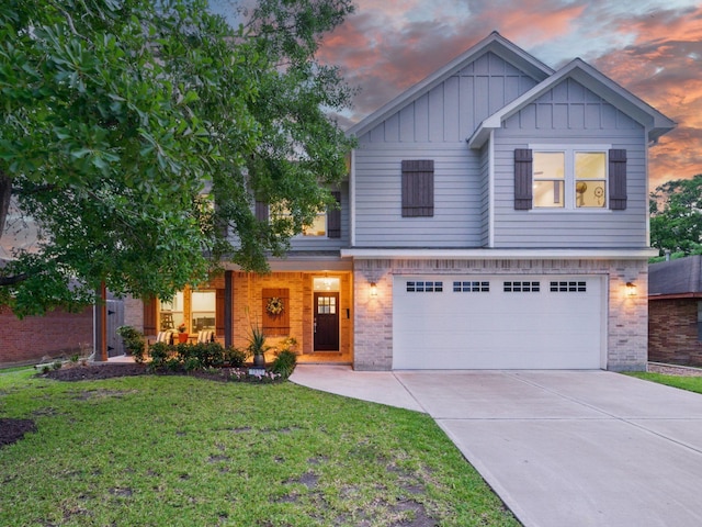 view of front facade with board and batten siding, brick siding, driveway, a yard, and an attached garage