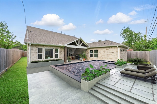 back of house with brick siding, a fenced backyard, roof with shingles, and a patio