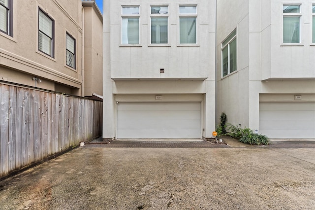 120 Pierce St, Houston, TX 77002 - exterior space featuring driveway, stucco siding, an attached garage, and fence