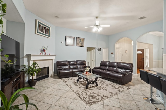 20714 Delta Wood Trl, Humble, TX 77346 - living room featuring ceiling fan, a tile fireplace, light tile patterned flooring, and arched walkways