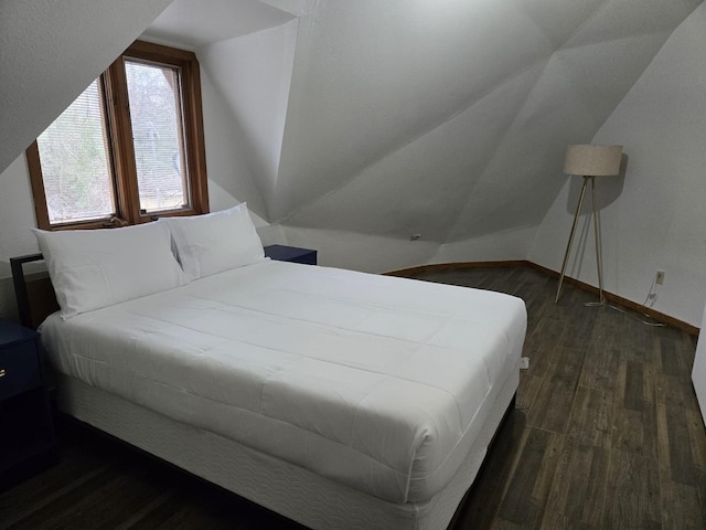 bedroom with lofted ceiling, dark wood-style flooring, and baseboards