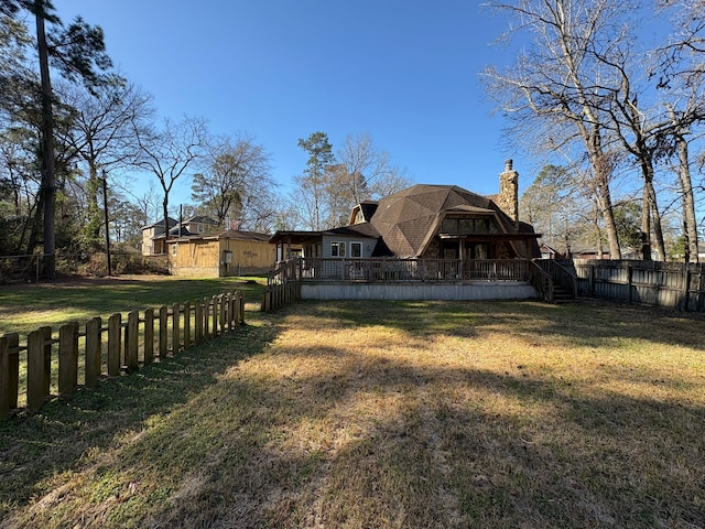 rear view of house featuring a yard, a chimney, a deck, and a fenced backyard