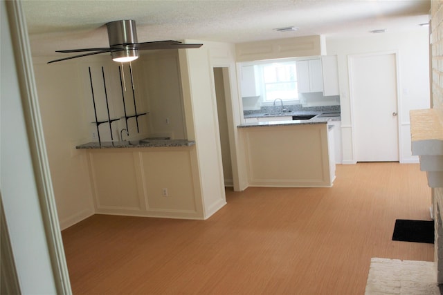 6103 Portal Dr, Houston, TX 77096 - kitchen with white cabinets, light wood finished floors, light stone countertops, and a sink