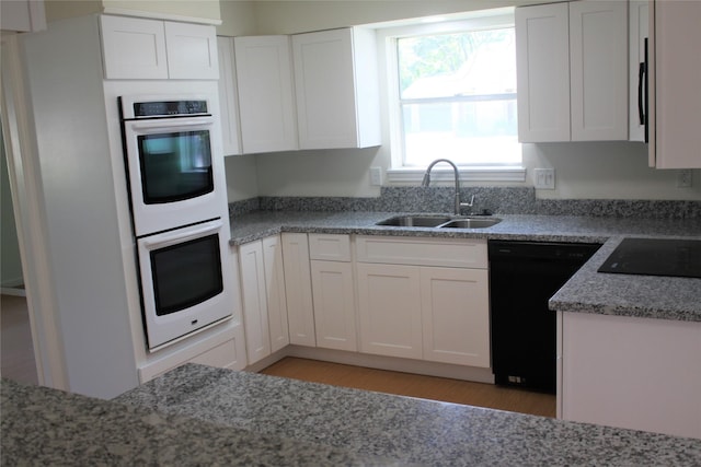 6103 Portal Dr, Houston, TX 77096 - kitchen with black appliances, a sink, white cabinetry, light stone counters, and light wood-style flooring