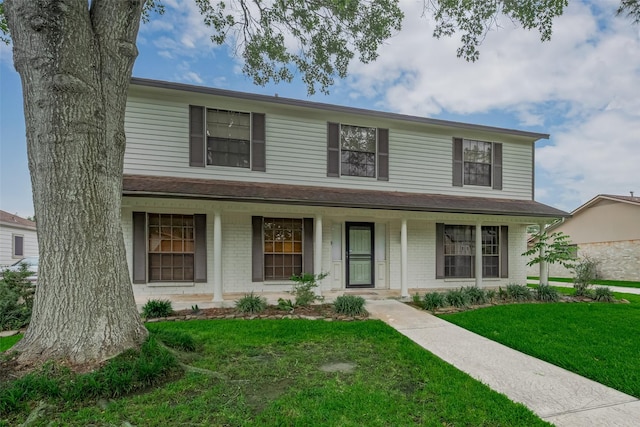 view of front of home featuring a front lawn, a porch, and brick siding