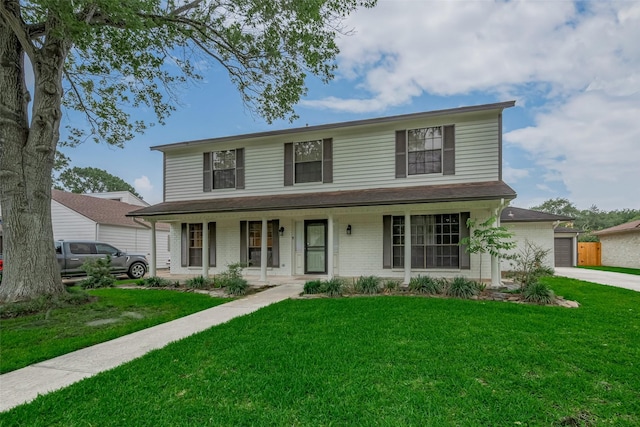 view of front of property featuring a porch, brick siding, a front yard, a garage, and driveway