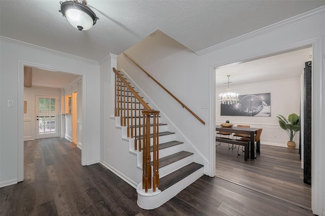 staircase with wood finished floors, crown molding, a chandelier, baseboards, and a textured ceiling