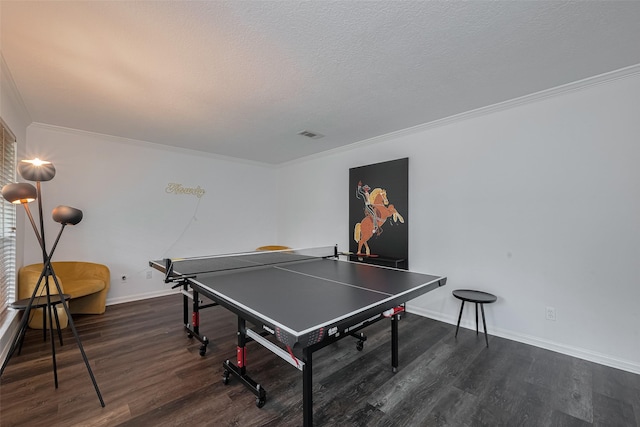 game room with dark wood-type flooring, ornamental molding, and baseboards