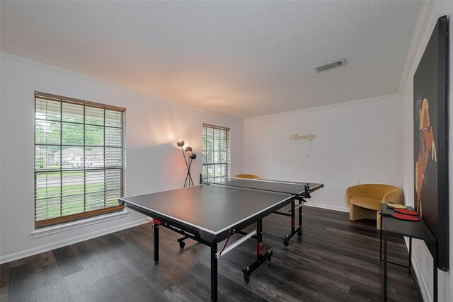 recreation room with ornamental molding, plenty of natural light, dark wood finished floors, and baseboards